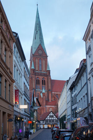 Blick von einer Häusergasse der Altstadt auf den Dom im Stil der Backsteingotik mit Kupferdach.