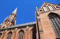 In einer Nahaufnahme der neugotische Paulskirche im schrägen Winkel aus Fußgängerperspektive zeigt sich ein starker Farbkontrast zwischen den braunen Backsteinen und dem blauen wolkenfreien Himmel.