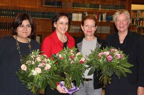 Marina Lorena Gutiérrez Botero, Dr. Pirko Kristin Zinnow, Silke Fischer und Tone Korssund-Eichinger halten lächelnd drei Blumensträuße. Im Hintergrund ist eine Bücherregalwand.