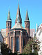 Die neugotische Paulskirche aus der Perspektive der Innenstadt zeigt die drei schmalen und hohen Türme gegen einen strahlend blauen Himmel.