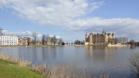 Der Blick vom Ufer des Burgsees richtet sich am anderen Ufer auf das rechts liegende Residenzschloss. Am linken Uferrand sind die weiteren Residenzgebäude.